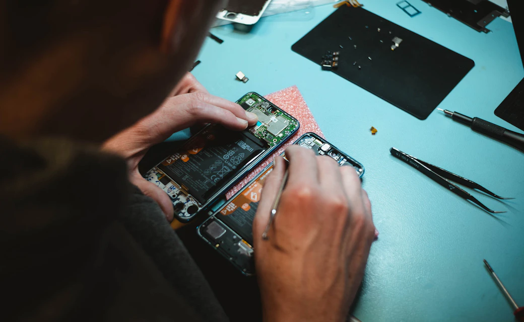 Técnico reparando un teléfono móvil sobre una mesa de trabajo.